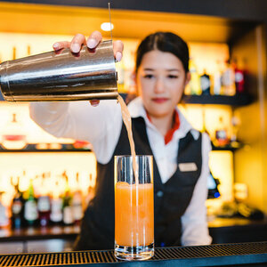 Bartender at the ATLANTIC Hotel Lübeck pours a cocktail into a glass at the stylish bar.