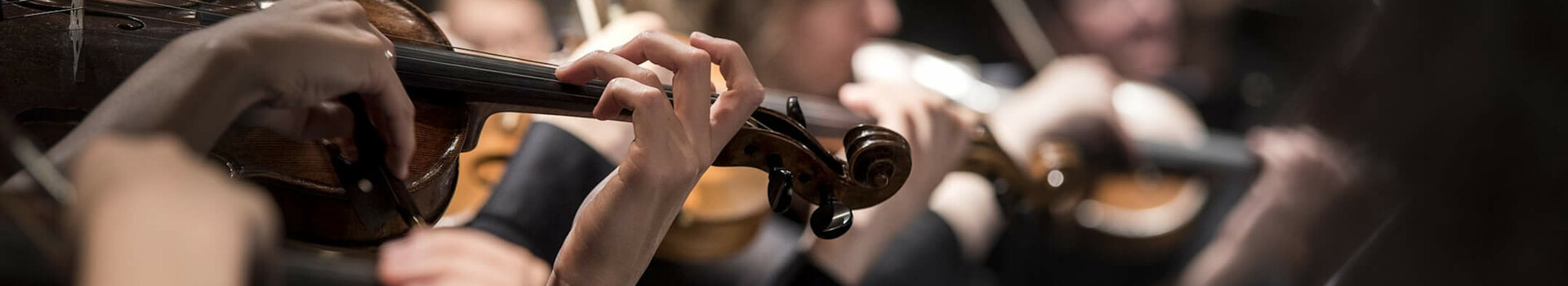 Musiker spielen Geigen in einem Orchester, Fokus auf die Hände und Instrumente.