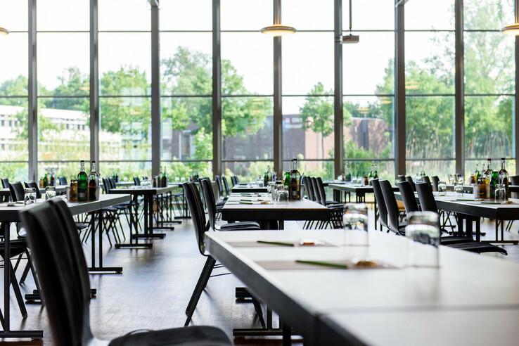 Heller, moderner Konferenzraum mit großen Fenstern, gedeckten Tischen und Blick ins Grüne im ATLANTIC Hotel Universum.