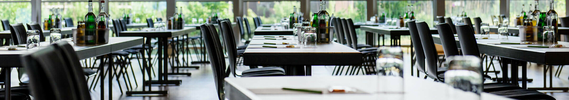 Heller, moderner Konferenzraum mit großen Fenstern, gedeckten Tischen und Blick ins Grüne im ATLANTIC Hotel Universum.