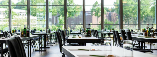 Heller, moderner Konferenzraum mit großen Fenstern, gedeckten Tischen und Blick ins Grüne im ATLANTIC Hotel Universum.