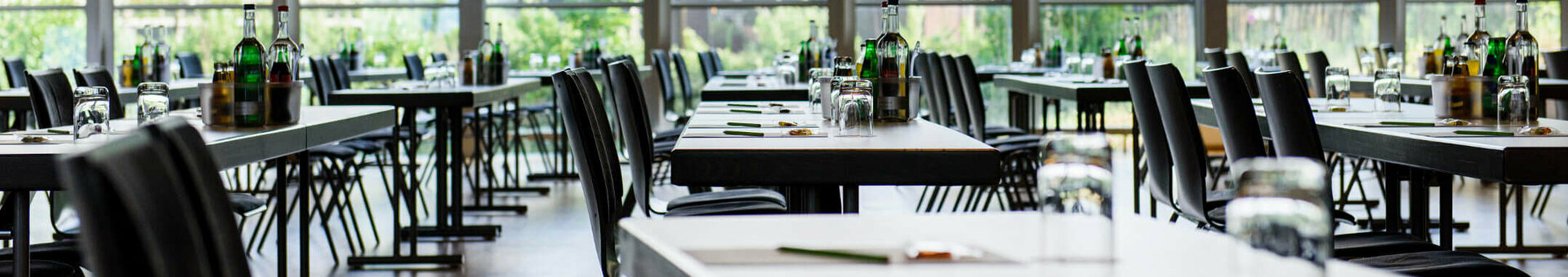 Bright, modern conference room with large windows, covered tables and a view of the greenery at the ATLANTIC Hotel Universum.