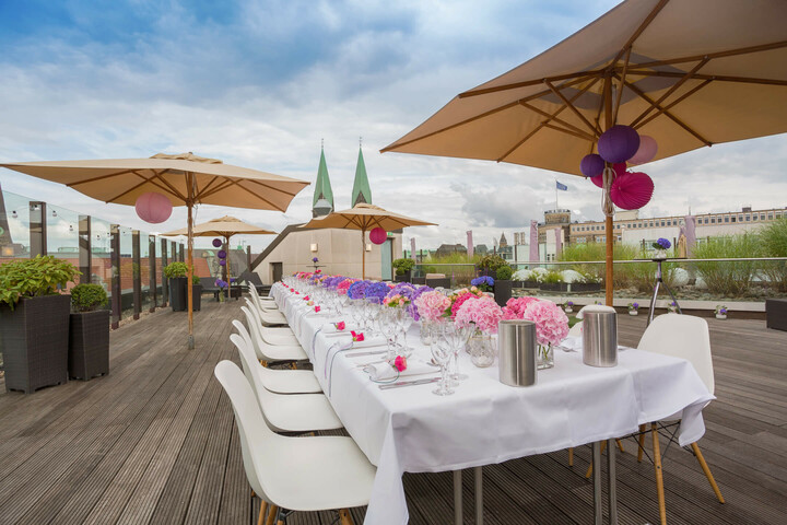 Hochzeitstafel mit bunter Blumendeko auf der Dachterrrasse des ATLANTIC Grand Hotel Bremen Dachterrasse mit festlich gedecktem Tisch, bunten Blumen und Sonnenschirmen im ATLANTIC Grand Hotel Bremen.