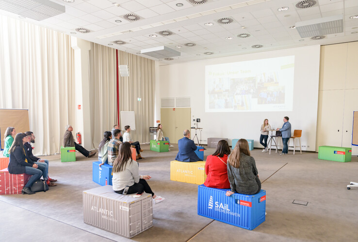 Seminarraum im ATLANTIC Hotel Sail City mit Teilnehmern auf bunten Kisten, Vortrag auf Leinwand.