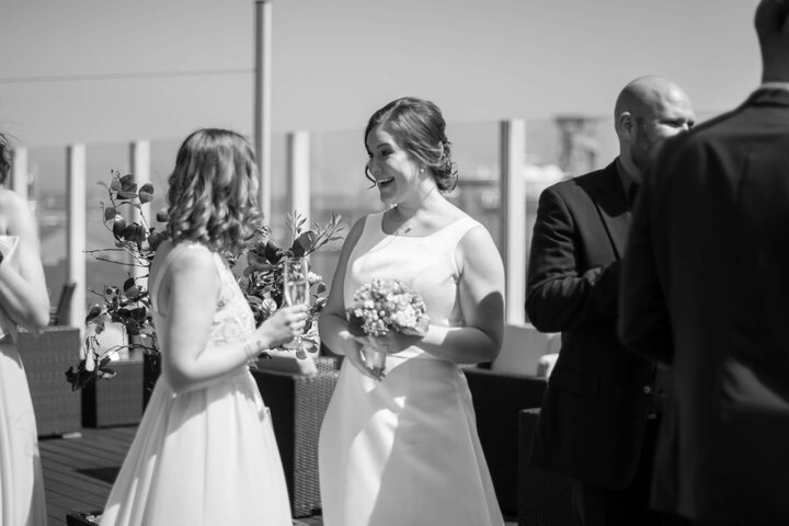 Bridal couple on the terrace of the ATLANTIC Hotel Kiel, laughing and with a bouquet of flowers.