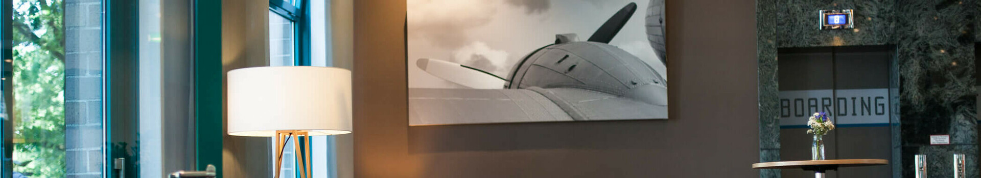 Customer event in the occasion of the room renovations | ATLANTIC Hotel Airport Modern hotel lobby with seating, large lamp and picture of an airplane on the wall at the ATLANTIC Hotel Airport Bremen.