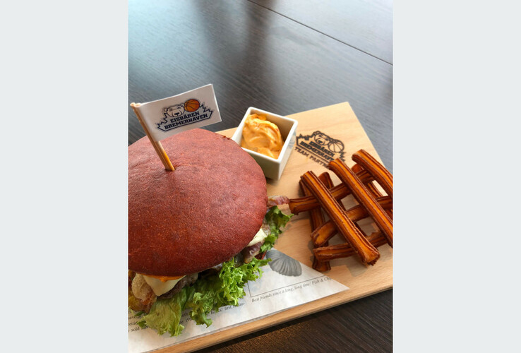 Burger with salad, fries and dip on a wooden board in the ATLANTIC Hotel Sail City Restaurant, Bremerhaven.
