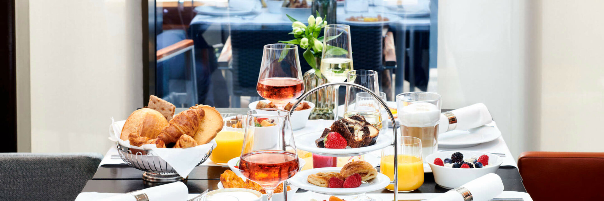 Elegant breakfast table at the ATLANTIC Grand Hotel Bremen with pastries, fruit, drinks and flower arrangements.