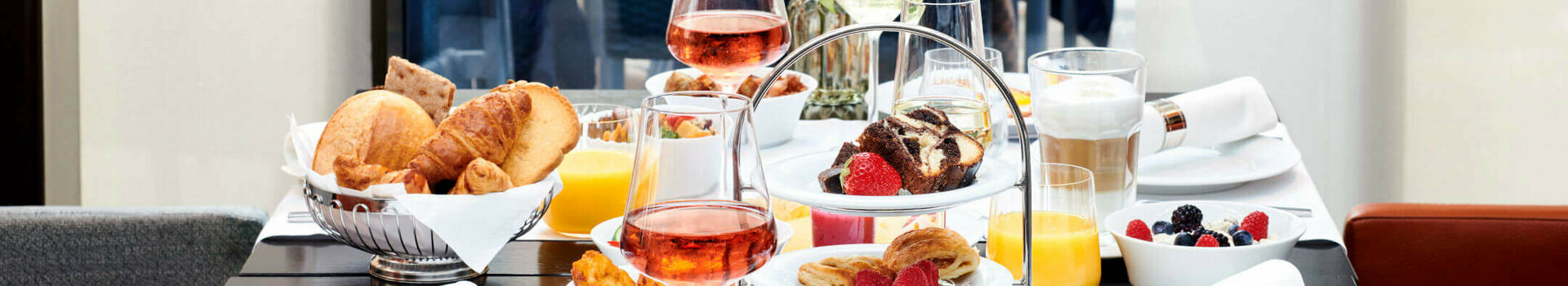 Eleganter Frühstückstisch im ATLANTIC Grand Hotel Bremen mit Gebäck, Obst, Getränken und Blumenarrangement.