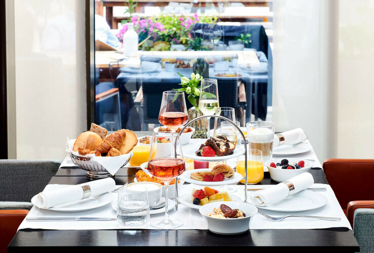 Elegant breakfast table at the ATLANTIC Grand Hotel Bremen with pastries, fruit, drinks and flower arrangements.