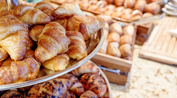 Frische Croissants und Brötchen auf einem Frühstücksbuffet im Hotel.