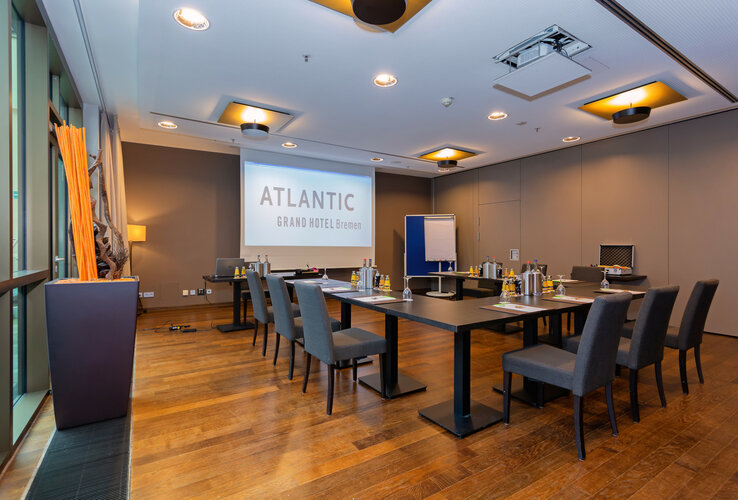 Moderner, heller Konferenzraum im ATLANTIC Grand Hotel Bremen mit Tischen, Stühlen und Präsentationstechnik.