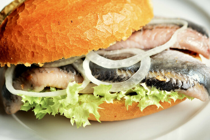 Frisches Fischbrötchen mit Zwiebeln und Salat auf knusprigem Brötchen.