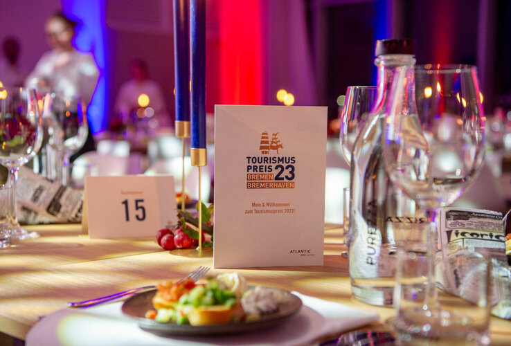 Festlich gedeckter Tisch im ATLANTIC Hotel Sail City, Bremerhaven, mit Menükarte "Tourismuspreis 2023" und Kerzen.