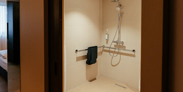 Ansicht der Dusche mit Sitz und Griffhaltern im barrierefreien Zimmer