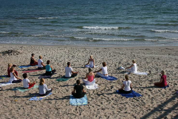 Gruppe beim Yoga am Strand mit Blick aufs Meer im ATLANTIC Grand Hotel Travemünde.