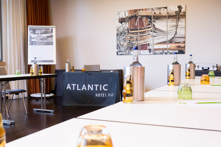 Konferenzraum im ATLANTIC Hotel Kiel mit Tischen, Getränken und einem Flipchart.