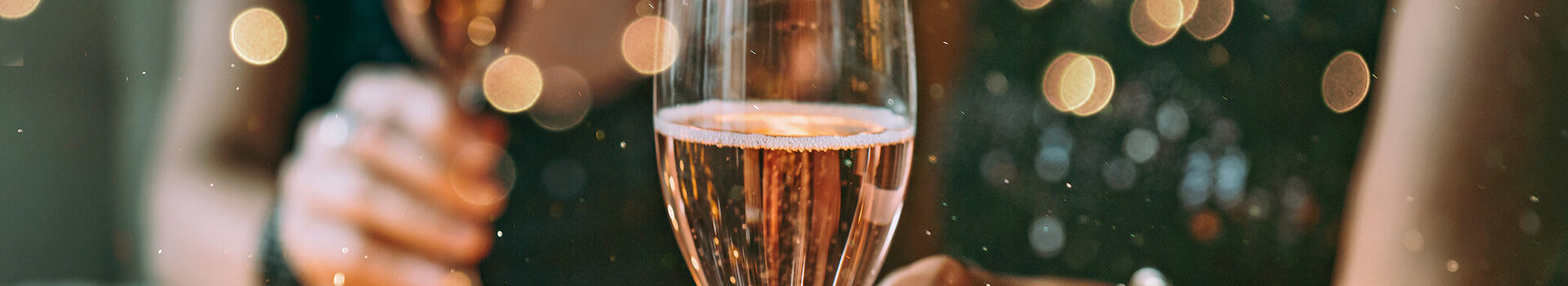 Two people are holding champagne glasses in a festive setting.