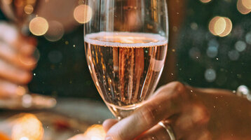 Zwei Menschen halten Champagnergläser in festlicher Dekoration.