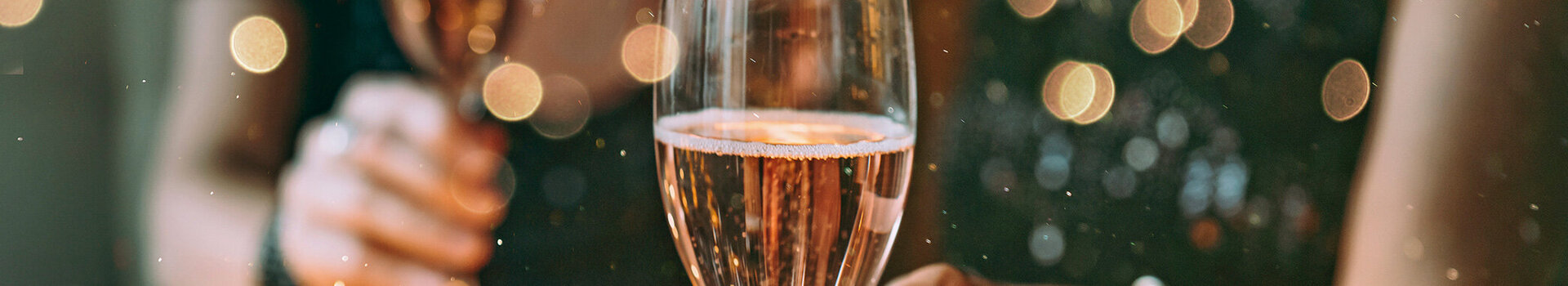 Zwei Menschen halten Champagnergläser in festlicher Dekoration.