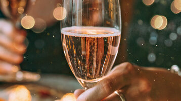 Zwei Menschen halten Champagnergläser in festlicher Dekoration.