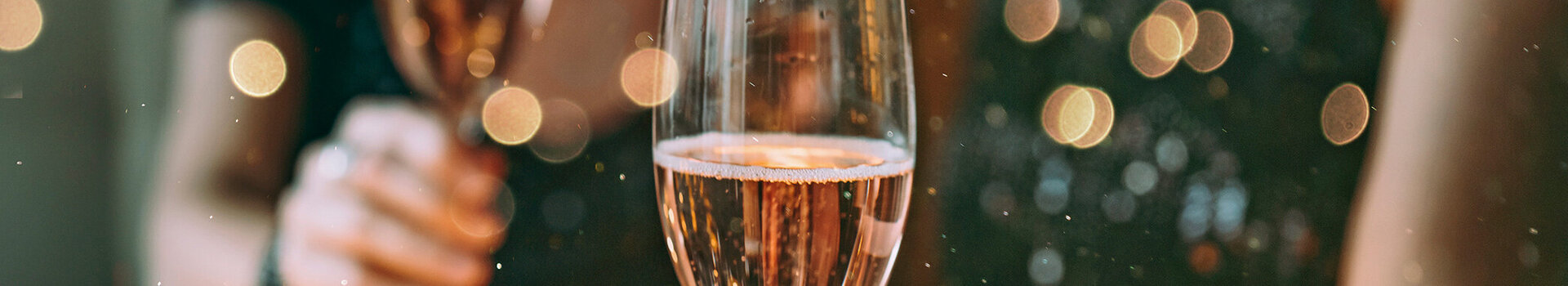 Zwei Menschen halten Champagnergläser in festlicher Dekoration.
