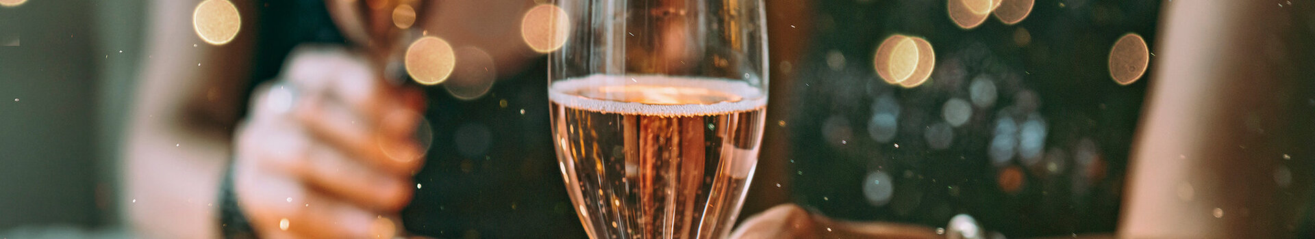 Zwei Menschen halten Champagnergläser in festlicher Dekoration.