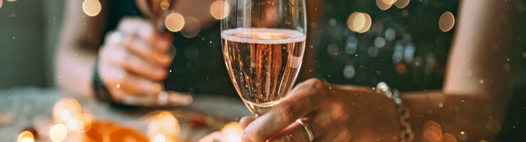 Zwei Menschen halten Champagnergläser in festlicher Dekoration.