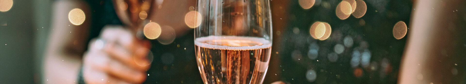 Zwei Menschen halten Champagnergläser in festlicher Dekoration.