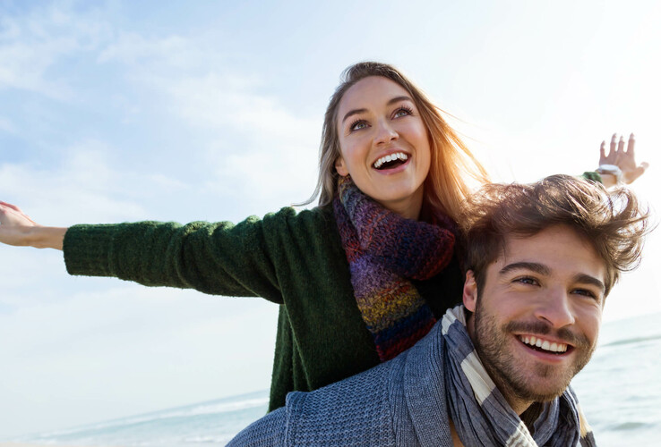 A smiling couple enjoys the sunny beach, which conveys joy and relaxation at the ATLANTIC Grand Hotel Travemünde.