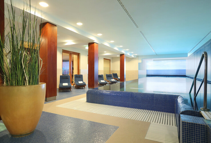 Bright indoor pool with sun loungers and plants at the ATLANTIC Grand Hotel Travemünde.