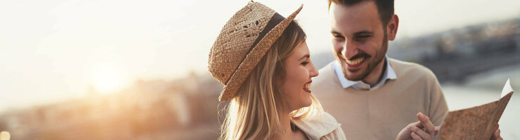ATLANTIC Hotel Galopprennbahn A smiling couple looks at a map at sunset on the riverbank.
