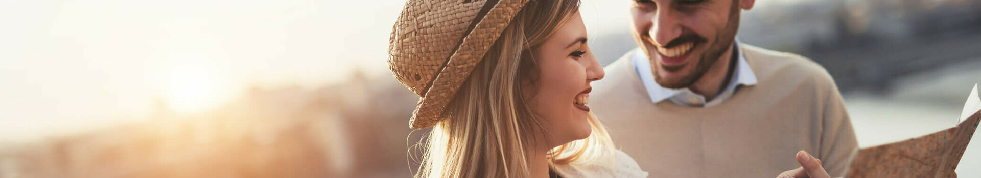 Ein lächelndes Paar betrachtet eine Karte bei Sonnenuntergang am Flussufer.