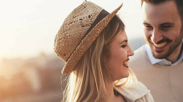 A smiling couple looks at a map at sunset on the riverbank.