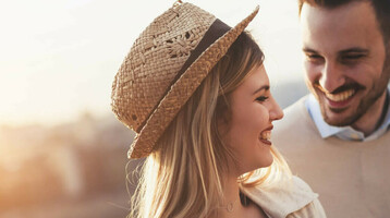 Ein lächelndes Paar betrachtet eine Karte bei Sonnenuntergang am Flussufer.