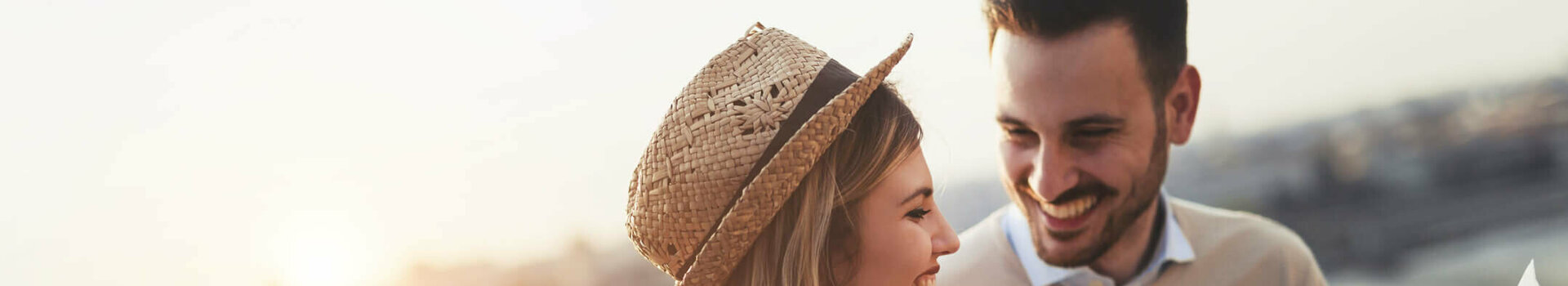 A smiling couple looks at a map at sunset on the riverbank.