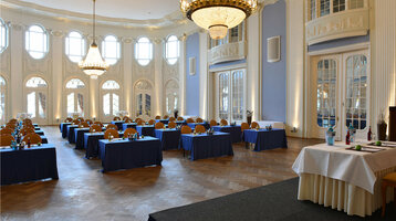 ATLANTIC Grand Hotel Travemünde Conference in the ballroom Elegant function room with chandeliers, blue tablecloths and a high ceiling at the ATLANTIC Grand Hotel Travemünde.