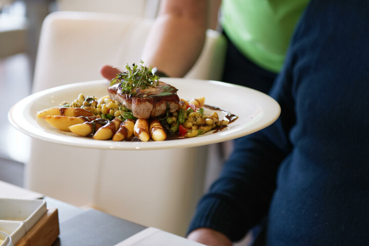 Ein Teller mit Steak, Gemüse und Kartoffeln wird in einem eleganten Restaurant serviert.