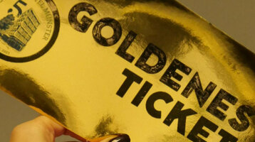 Eine Hand, die ein goldenes spiegelndes Ticket hält, mit der Aufschrift "Goldenes Ticket"