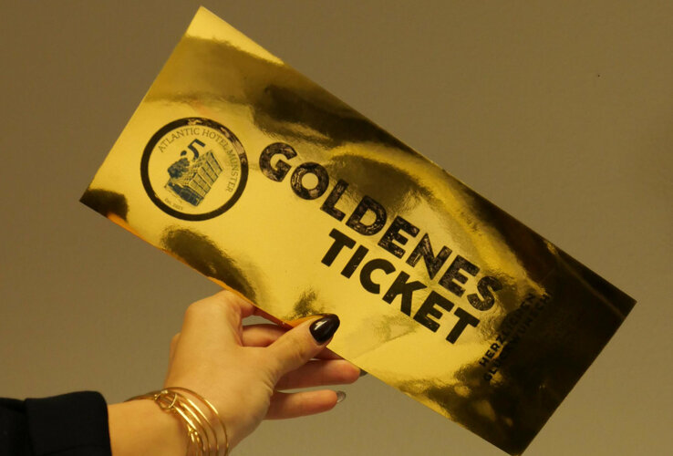 Eine Hand, die ein goldenes spiegelndes Ticket hält, mit der Aufschrift "Goldenes Ticket"