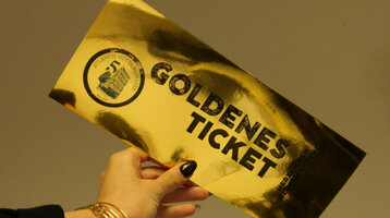 Eine Hand, die ein goldenes spiegelndes Ticket hält, mit der Aufschrift "Goldenes Ticket"