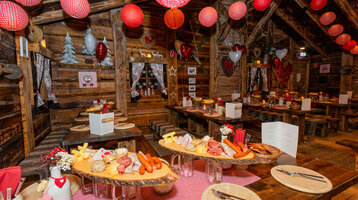 ATLANTIC Grand Hotel Bremen Almhütte Rabattaktion Cozy mountain hut with wooden tables, decorated with red lanterns and a hearty buffet at the ATLANTIC Grand Hotel Bremen.