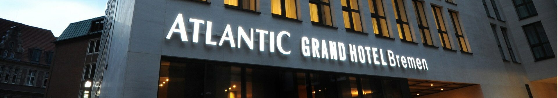 Exterior view of the ATLANTIC Grand Hotel Bremen at twilight  Facade of the ATLANTIC Grand Hotel Bremen with illuminated hotel entrance at dusk.