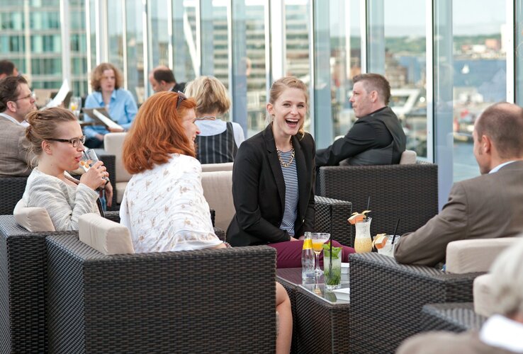 Bar DECK 8 in Kiel im ATLANTIC Hotel Kiel Menschen genießen Getränke auf der Terrasse des ATLANTIC Hotel Kiel mit Blick auf die Stadt.