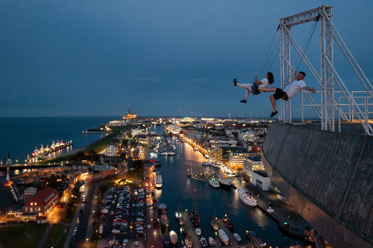 Zwei Personen die auf der High Swing auf dem ATLANTIC Hotel Sail City Schaukeln. KI Mockup