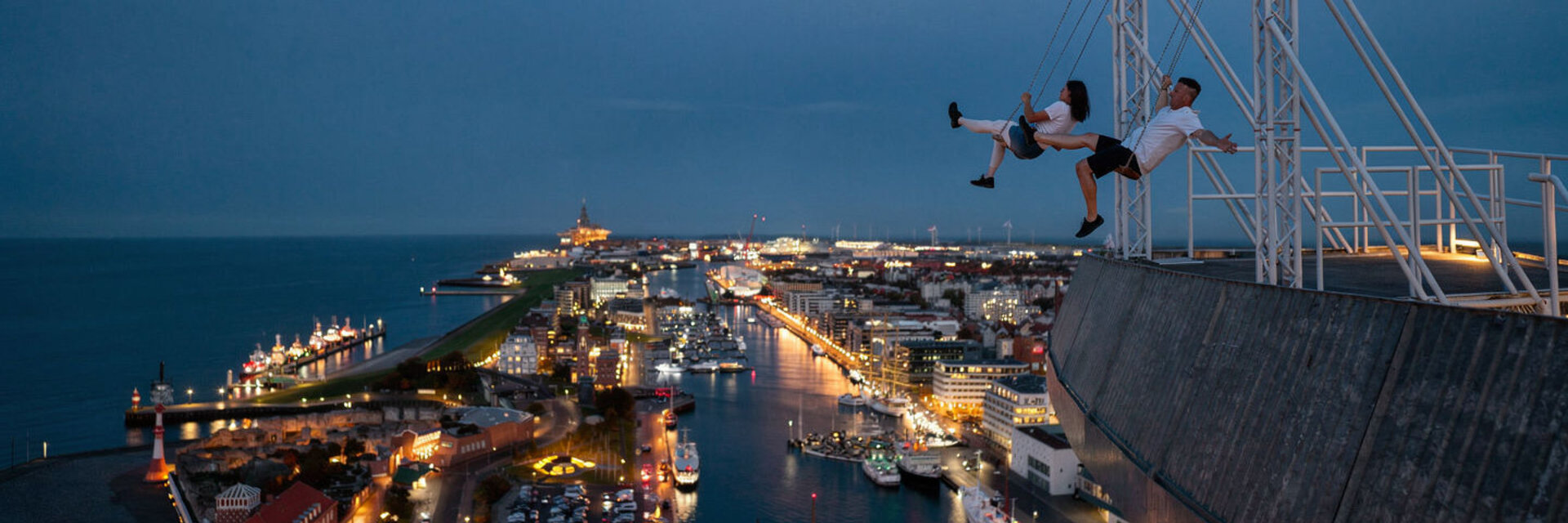 Zwei Personen die auf der High Swing auf dem ATLANTIC Hotel Sail City Schaukeln. KI Mockup