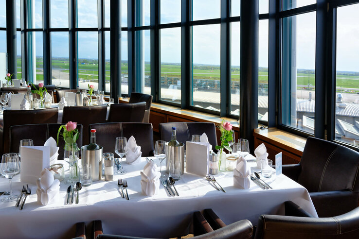 Elegant restaurant in the ATLANTIC Hotel Airport with set tables and large windows overlooking the tarmac.