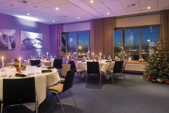 Abendliche Weihnachtsfeier im ATLANTIC Hotel Airport Bremen Festlich gedeckter Veranstaltungsraum im ATLANTIC Hotel Airport Bremen mit Kerzenlicht und Weihnachtsbaum.