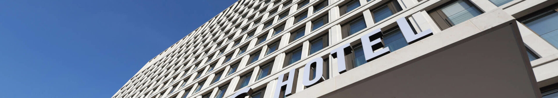 Fassade des ATLANTIC Hotels Heidelberg, modernes Hochhaus mit blauem Himmel im Hintergrund.