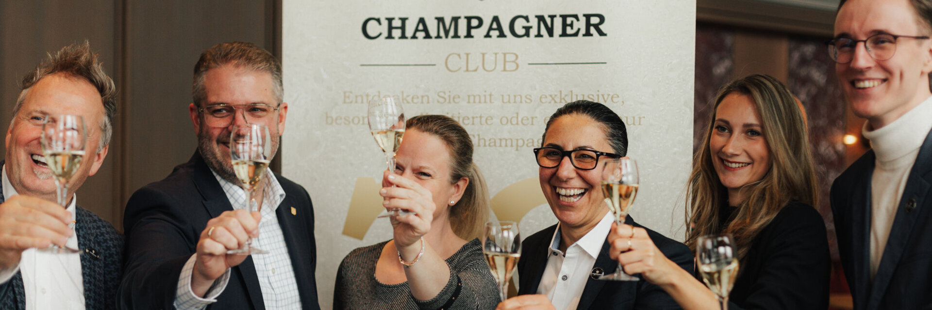 Menschen halten lachend ein Glas Champagner.